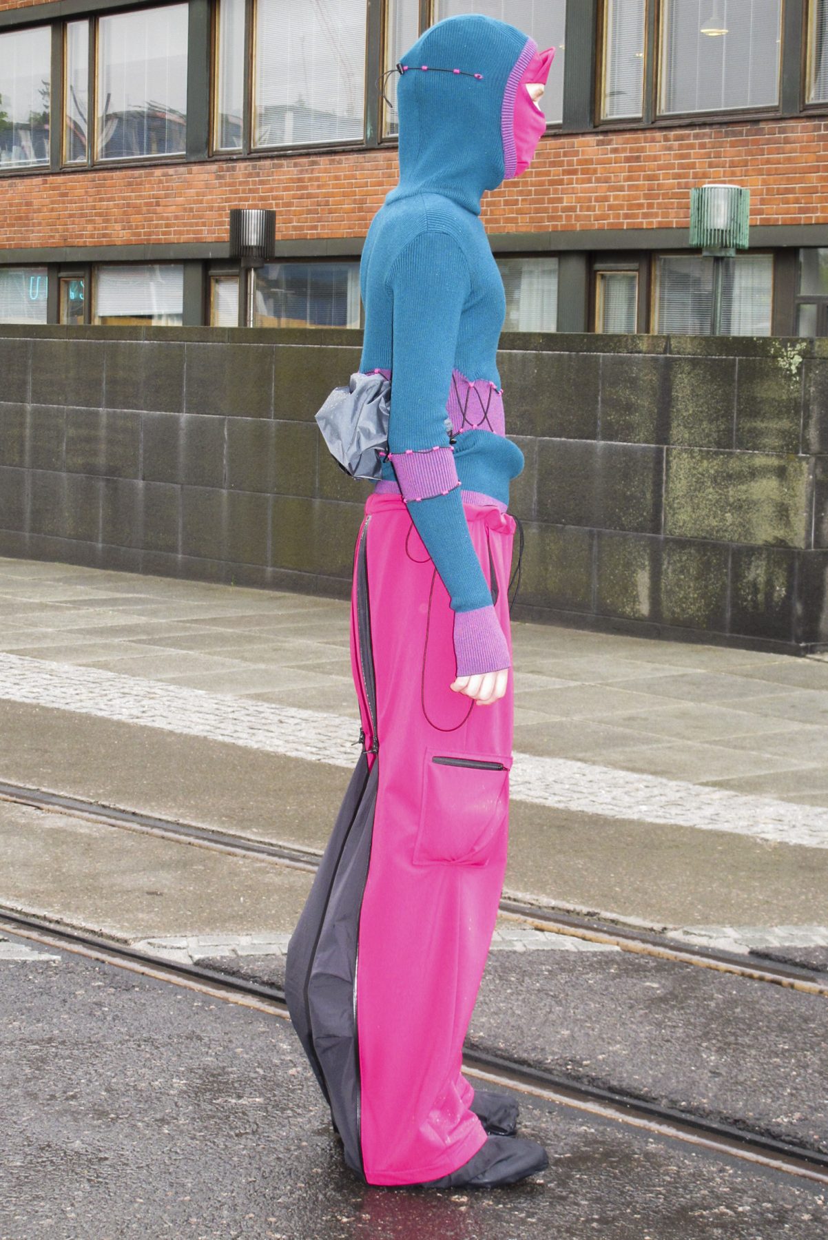 Side view of model wearing a turquoise hoodie and pink-black outdoor pants