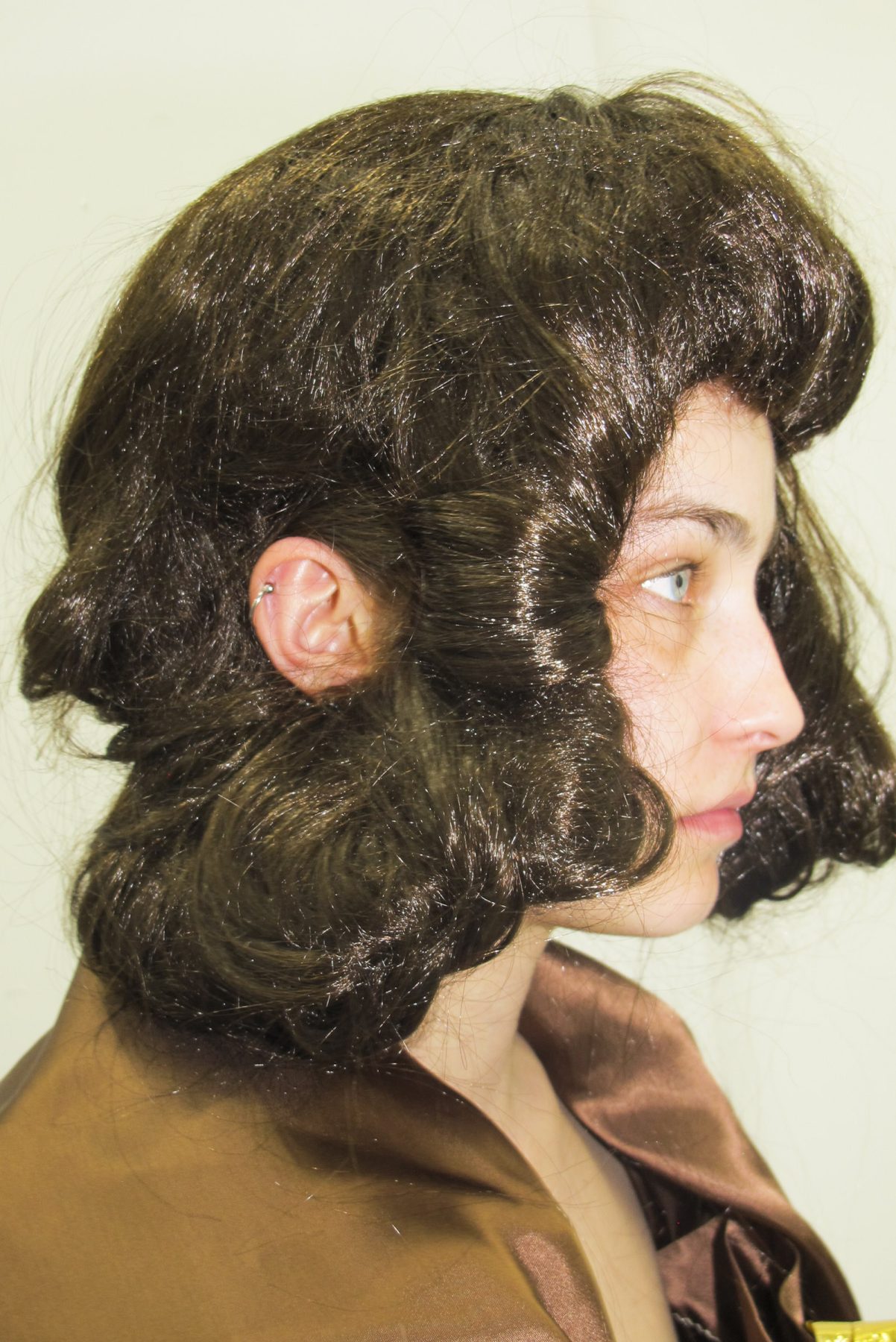 Close up of model wearing a brown puffy wig with ear visible