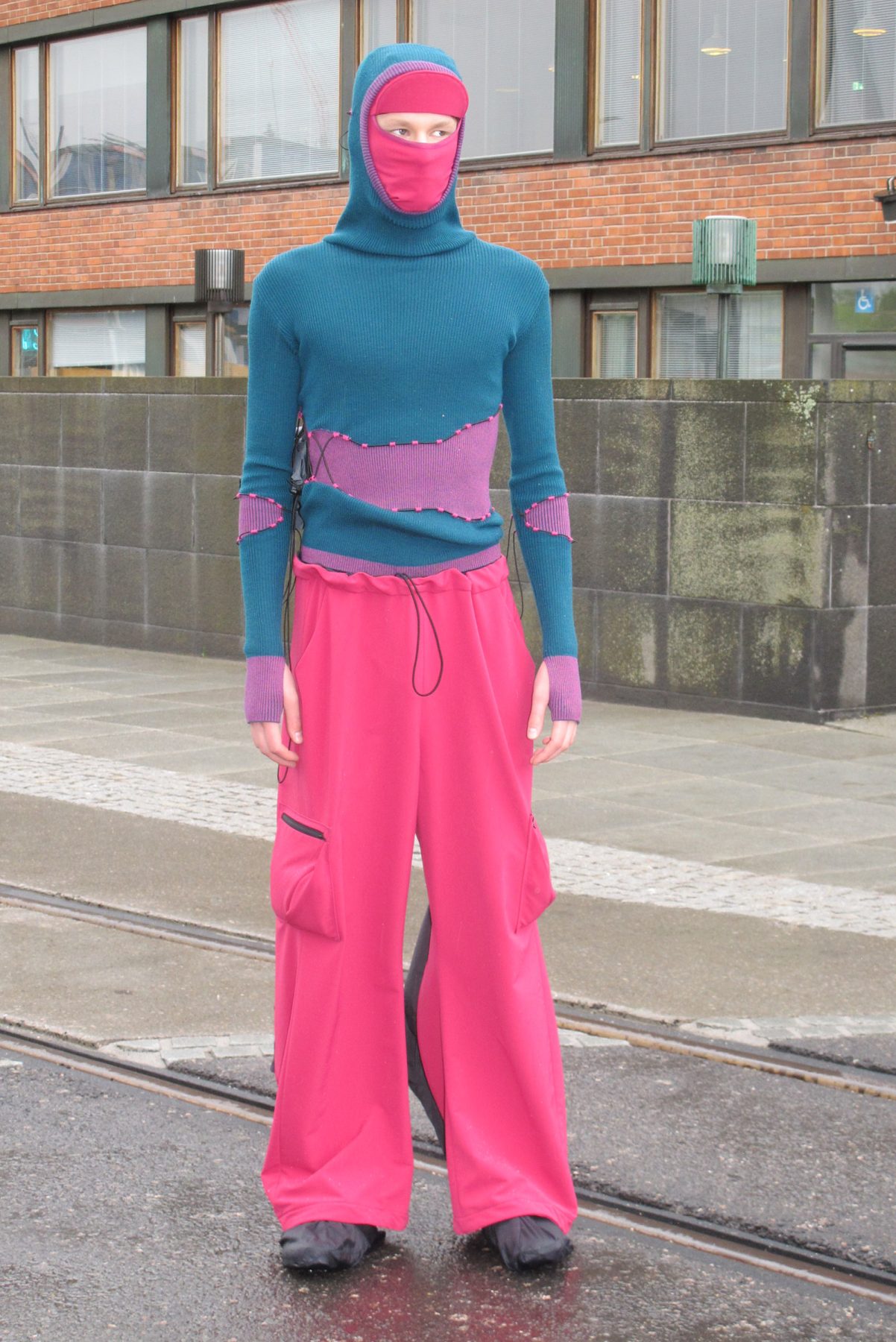 Model is wearing a turquoise hoodie and pink-black outdoor pants
