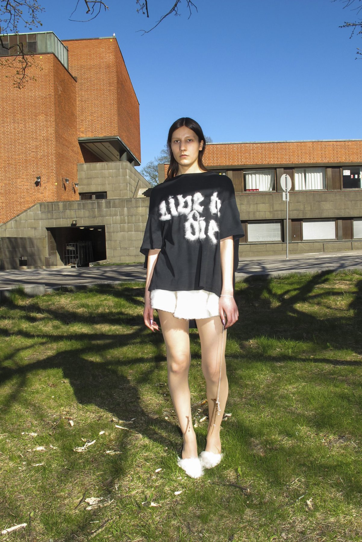 Model is wearing a black t-shirt with text and short white skirt