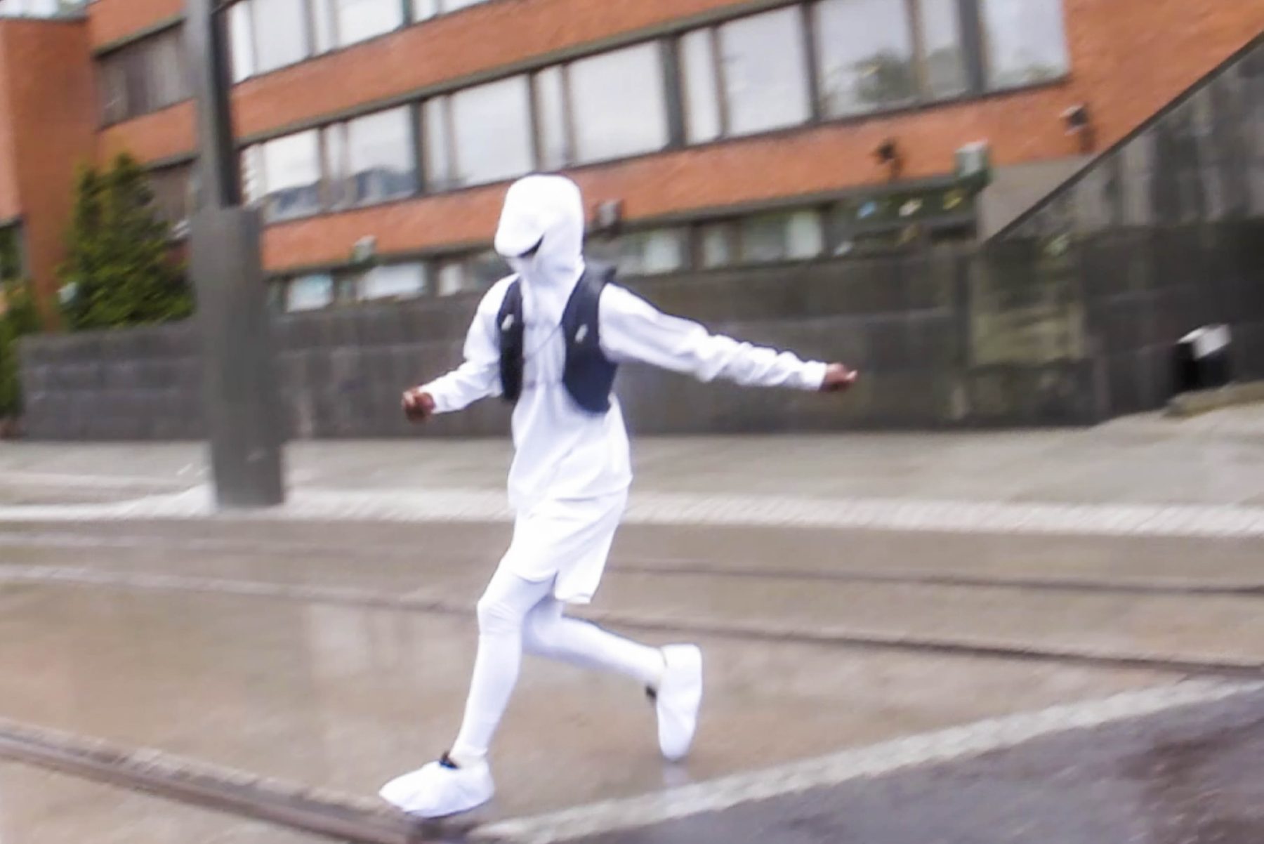 Photo of model running in rain wearing white weatherproof outfit