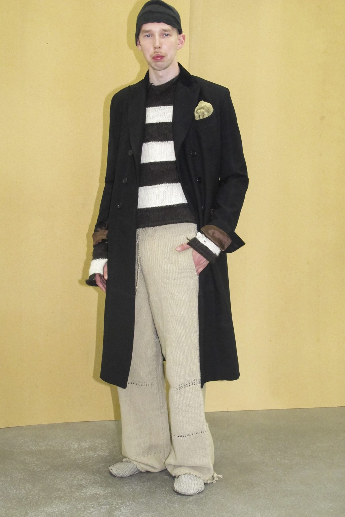 Photo of model wearing striped jumper, black coat and beige trousers