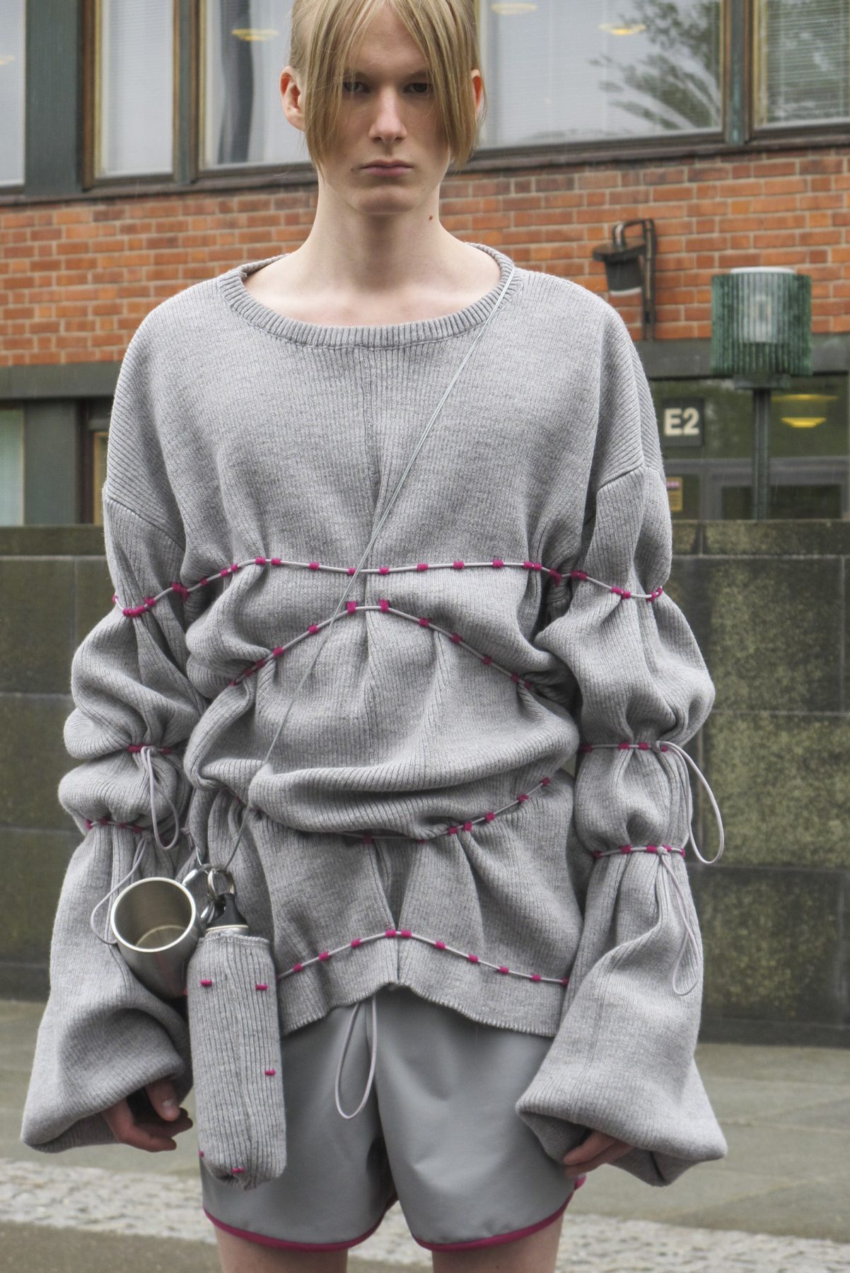 Photo of model wearing draped grey jumper with strings