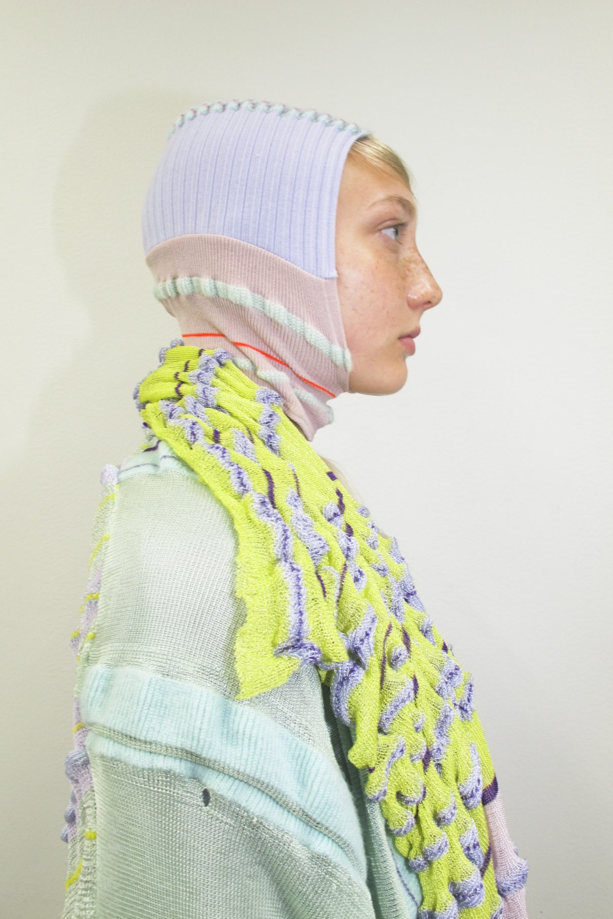 Model wearing knitted striped balaclava and long striped scarf