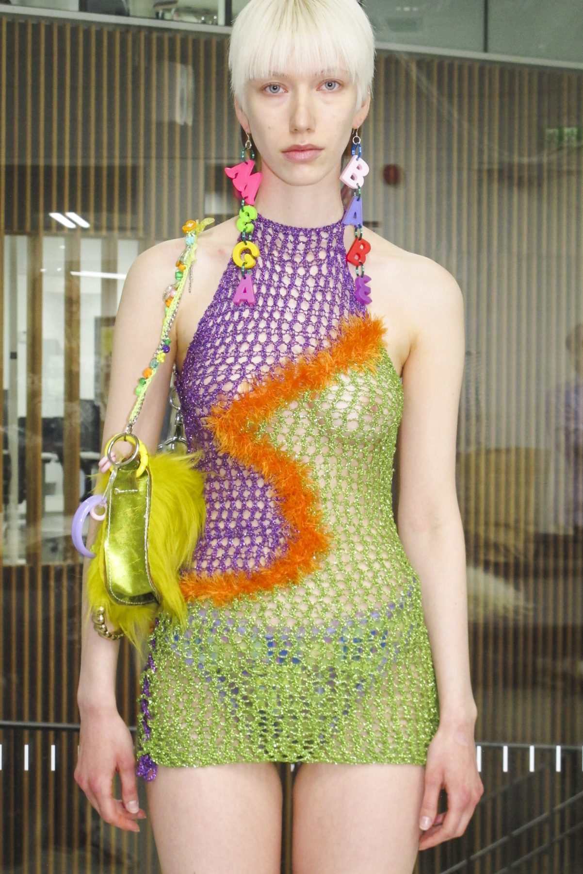 Photo of model wearing short colorful crochet dress and megababe earrings