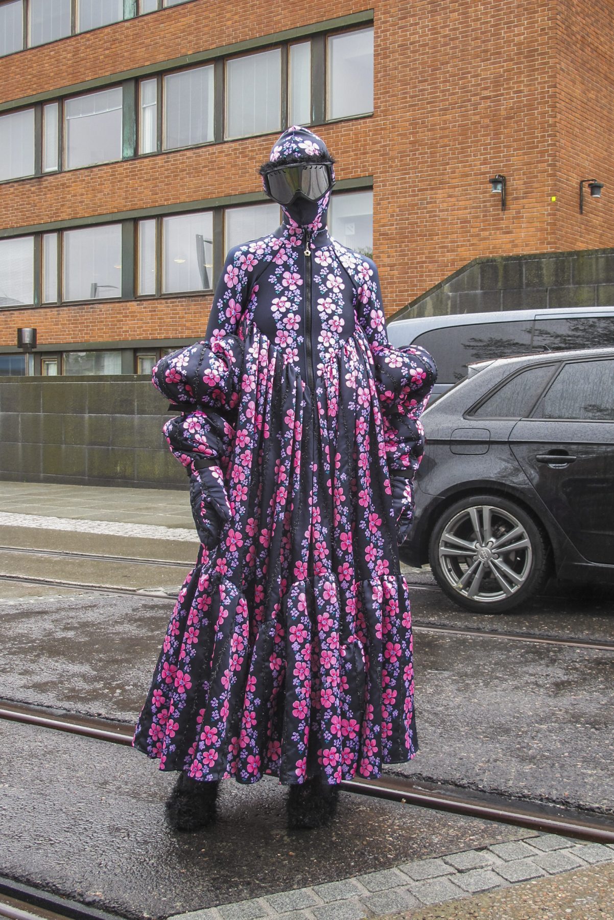 Photo of model wearing black printed floral dress with matching balaclava and skiing goggles