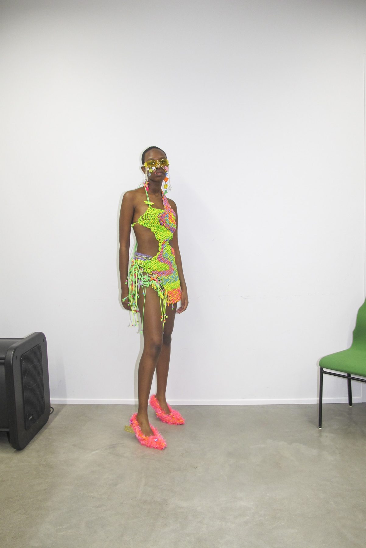 Photo of model wearing short colorful beaded dress and decorated eyeglasses