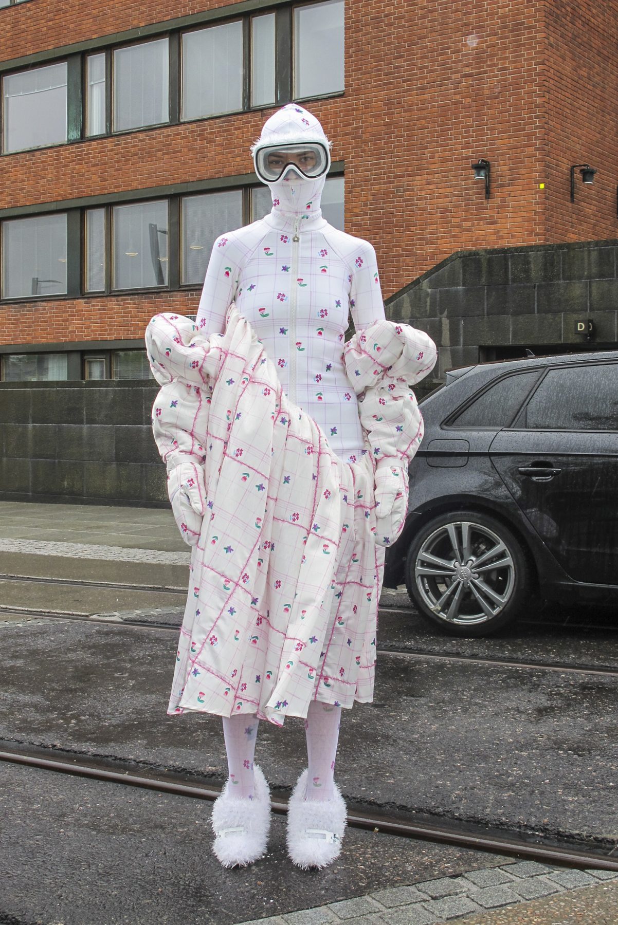 Photo of model wearing white floral-printed dress with puffy sleeves, matching balaclava and skiing goggles