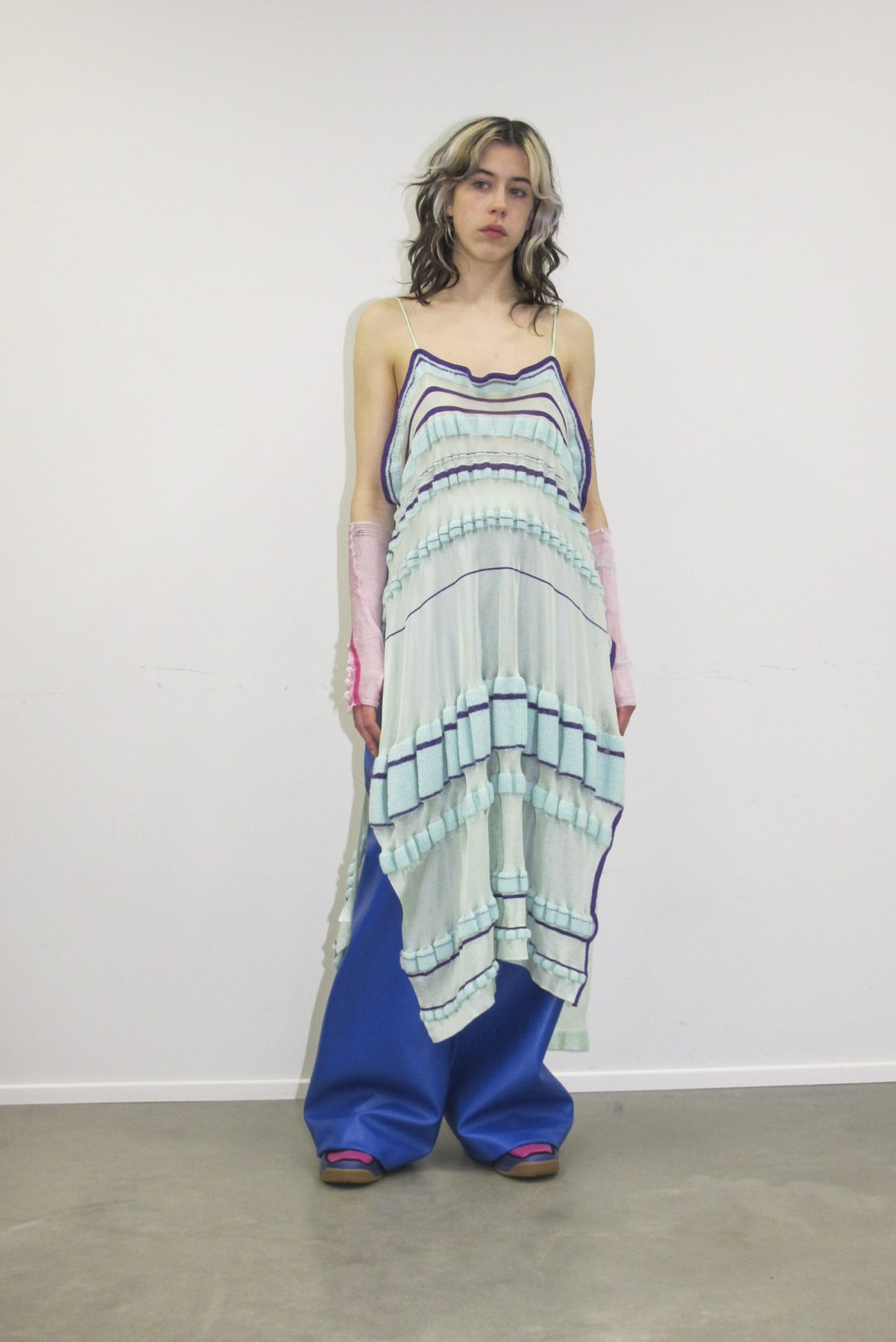 Photo of model wearing knitted striped mint dress and long ultramarine trousers