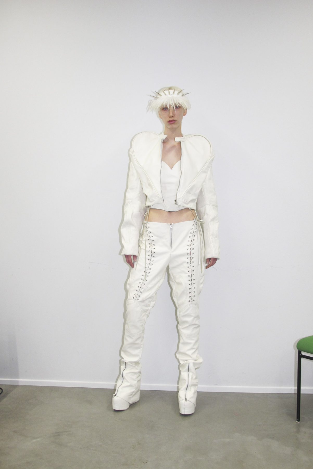 Photo of model wearing white puffy and spiked hairband, white puffy-sleeved leather jacket and leather pants with braided details