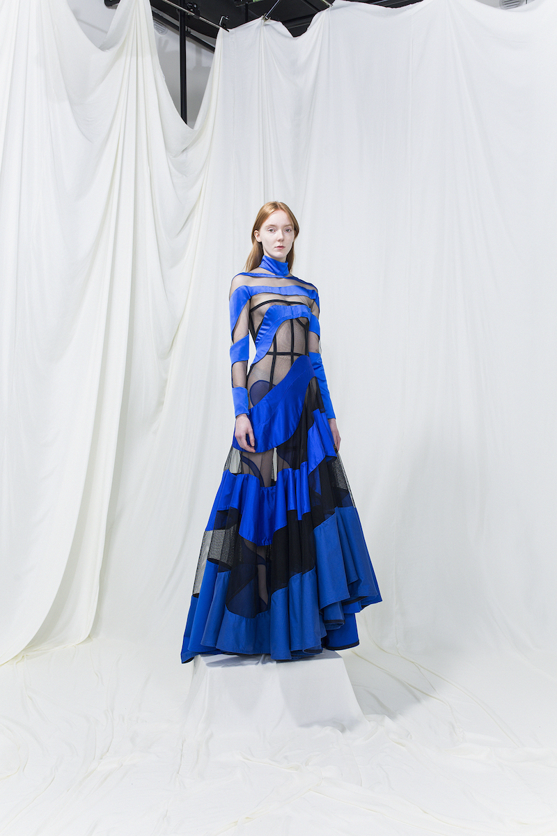 Model wearing a long blue dress with black mesh cutouts.
