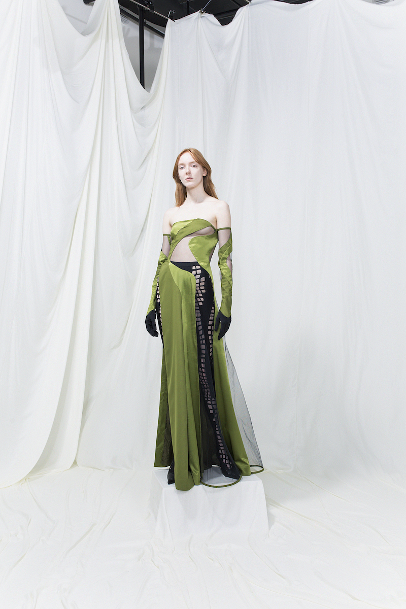 Model wearing a green long dress with cut-outs, cut-out leggings underneath