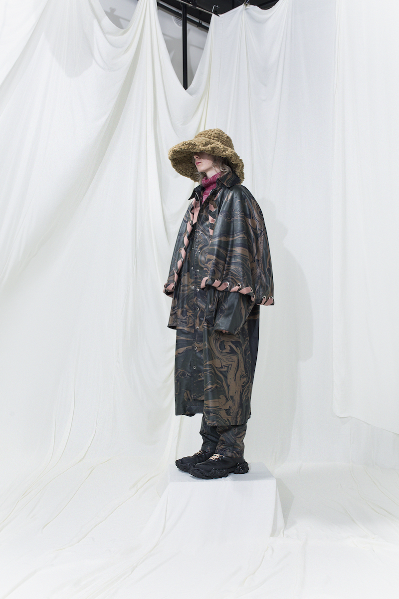 Long marble printed coat with extra cape worn with long marble-printed trousers. Brushed fur hat