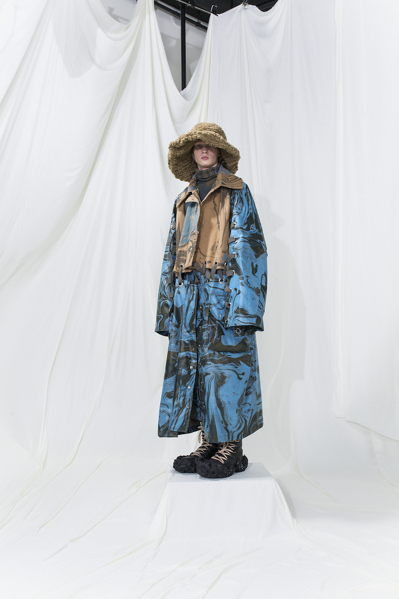 Marble printed machintosh coat in light blue and beige panels, connected with eyelets. Brushed fur hat
