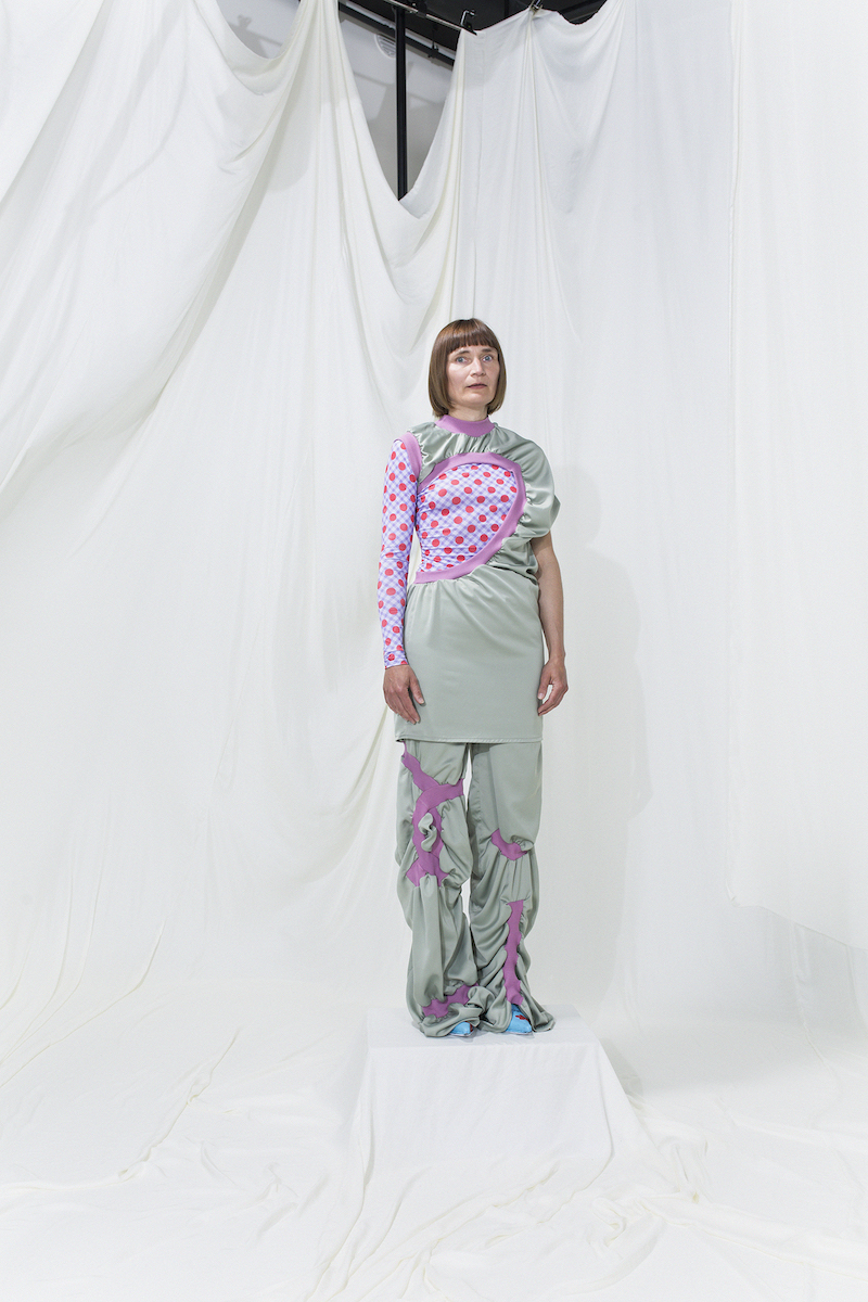 Model is wearing an asymmetrical gathered dress with hole with printed top and gathered trousers underneath