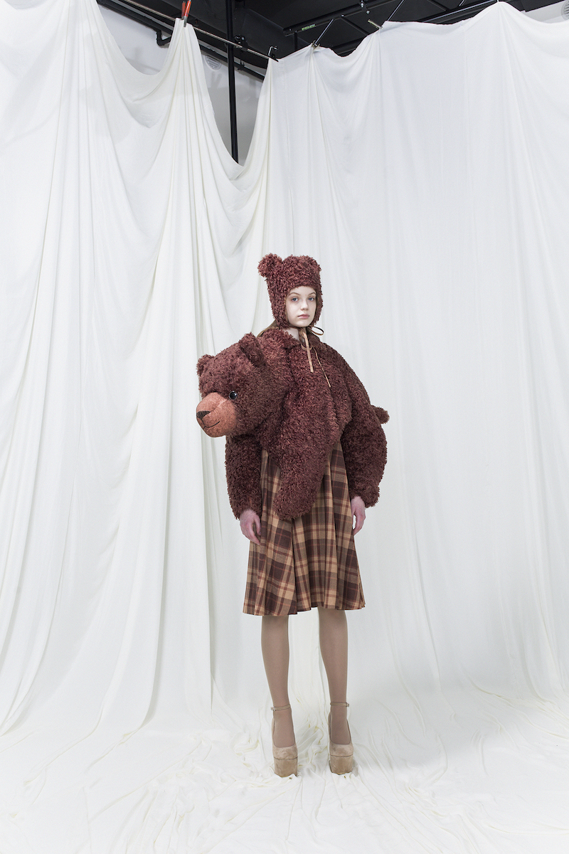 Model wearing brown brushed fur resembling a stuffed bear, brown checked dress underneath and a brushed fur hat with ears.