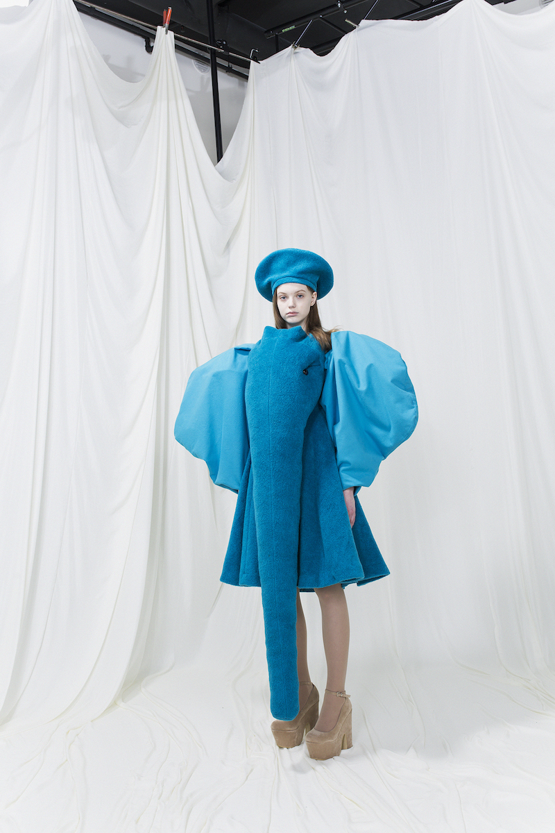Model wearing blue dress resembling an elephant, balloon sleeves and trunk in the front. Blue beret.