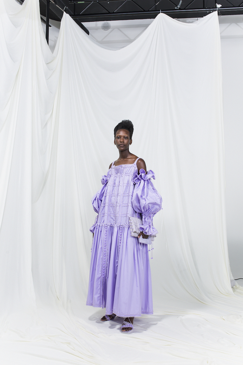 Model is wearing a lilac modular silk dress with oversized sleeves and matching violet heels