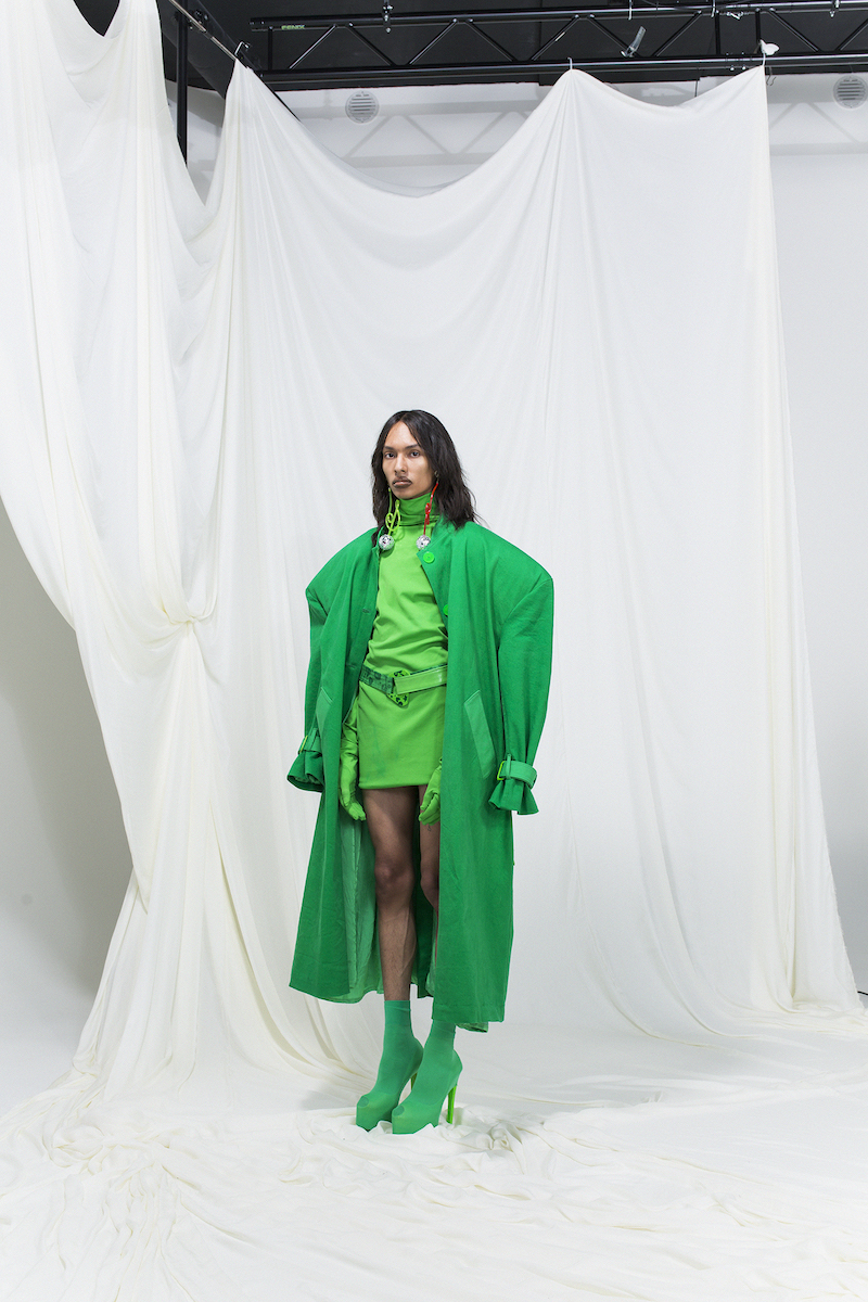 Model wearing a bright green trench coat with green dress, gloves and green high heels.