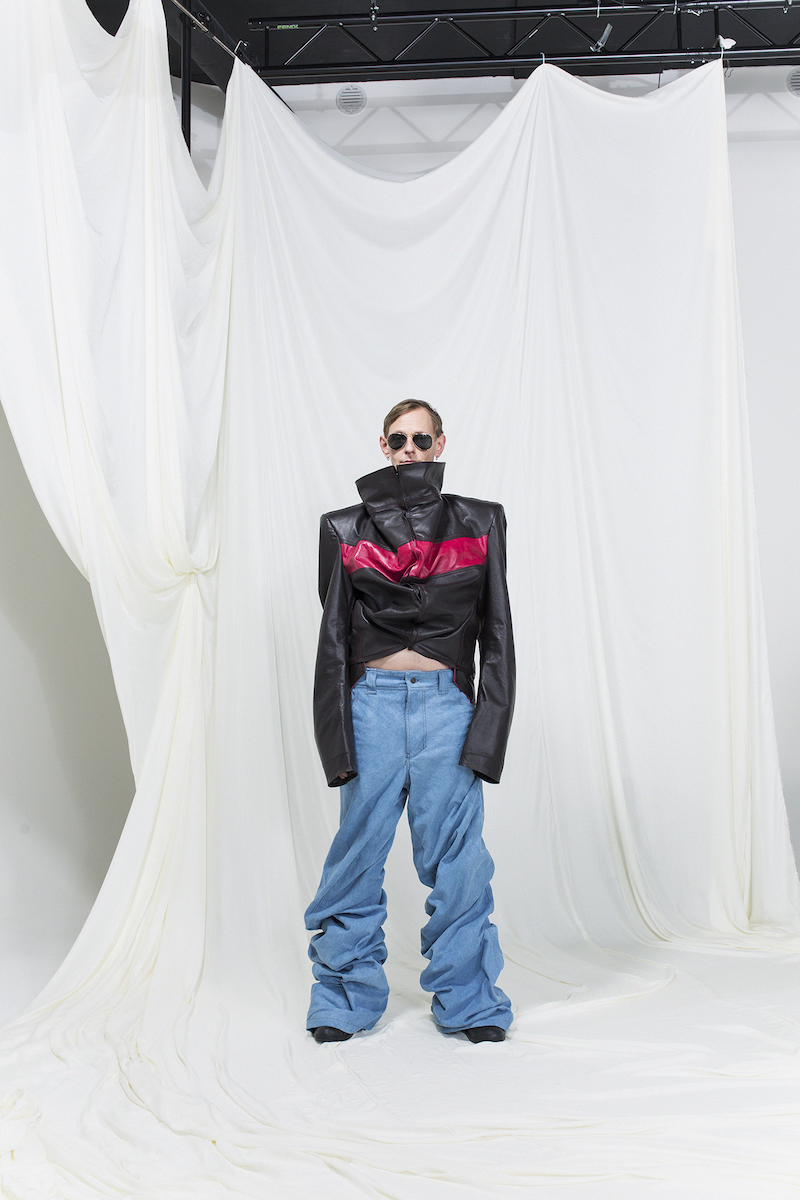 Model is wearing a oversized leather jacket with red stripe and oversized jeans