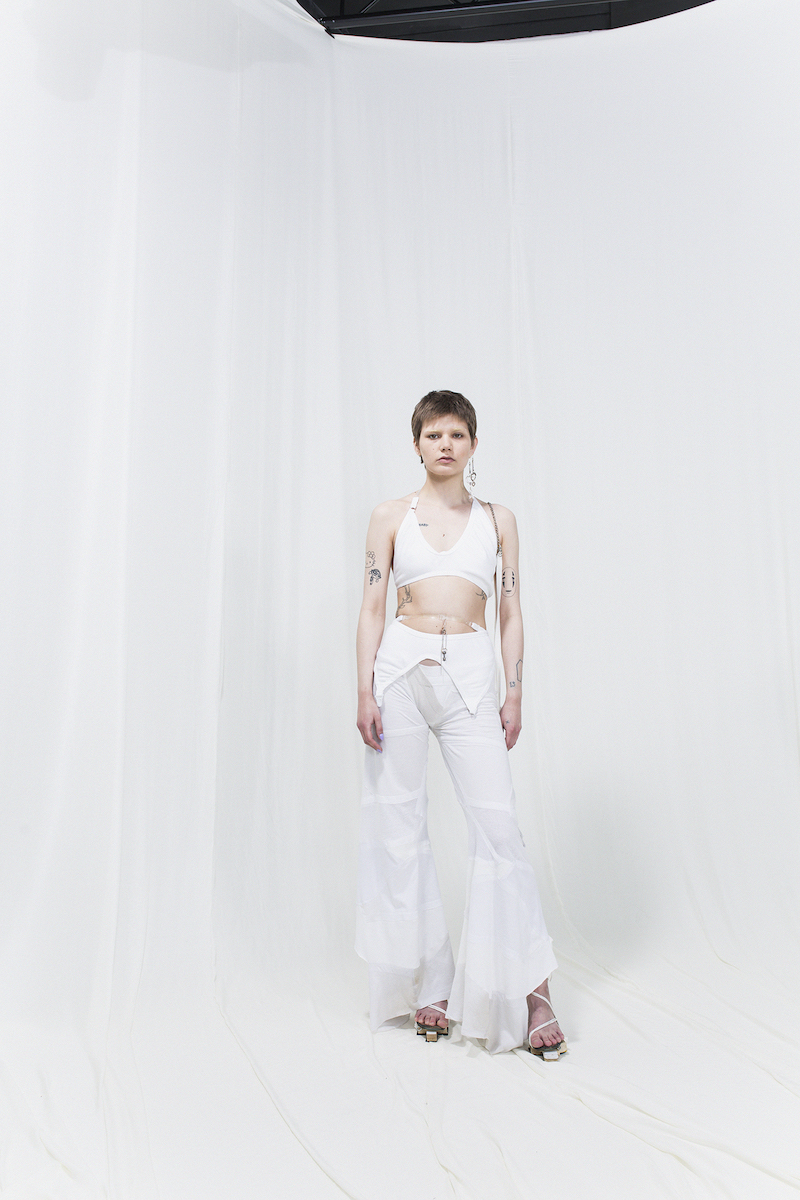 Model is wearing a white top and white bell-bottomed draped trousers