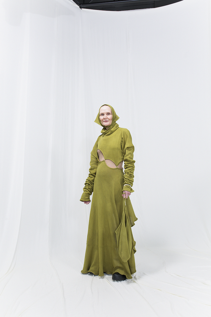 Model is wearing a long knitted green dress with matching bag and headscarf