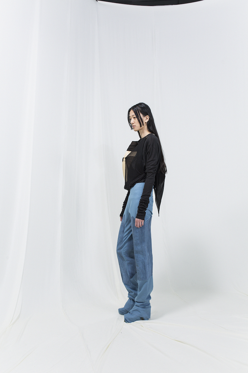 Model is wearing a black jersey sweater with bended birch piece attached, with blue jeans.