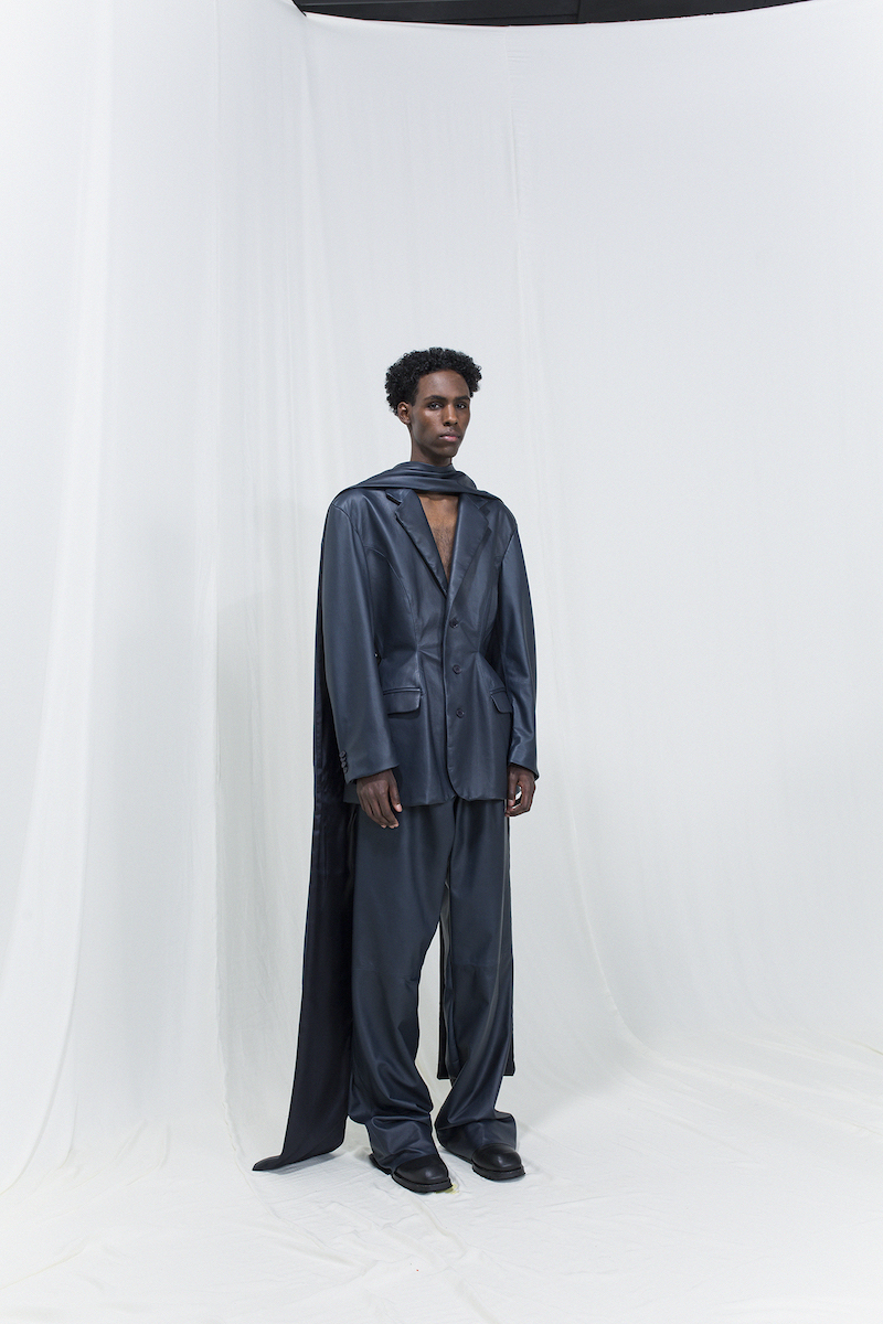 Model is wearing a metallic dark blue blazer and matching oversized trousers.