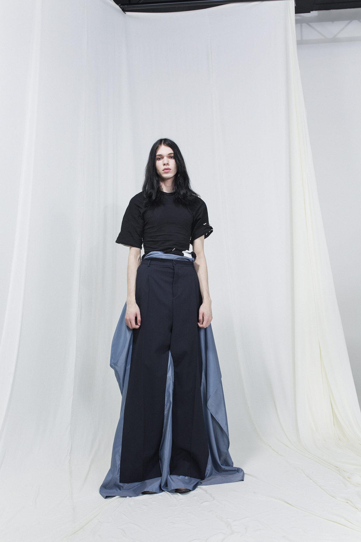 Model wearing a black t-shirt with gray-blue skirt with trousers on top